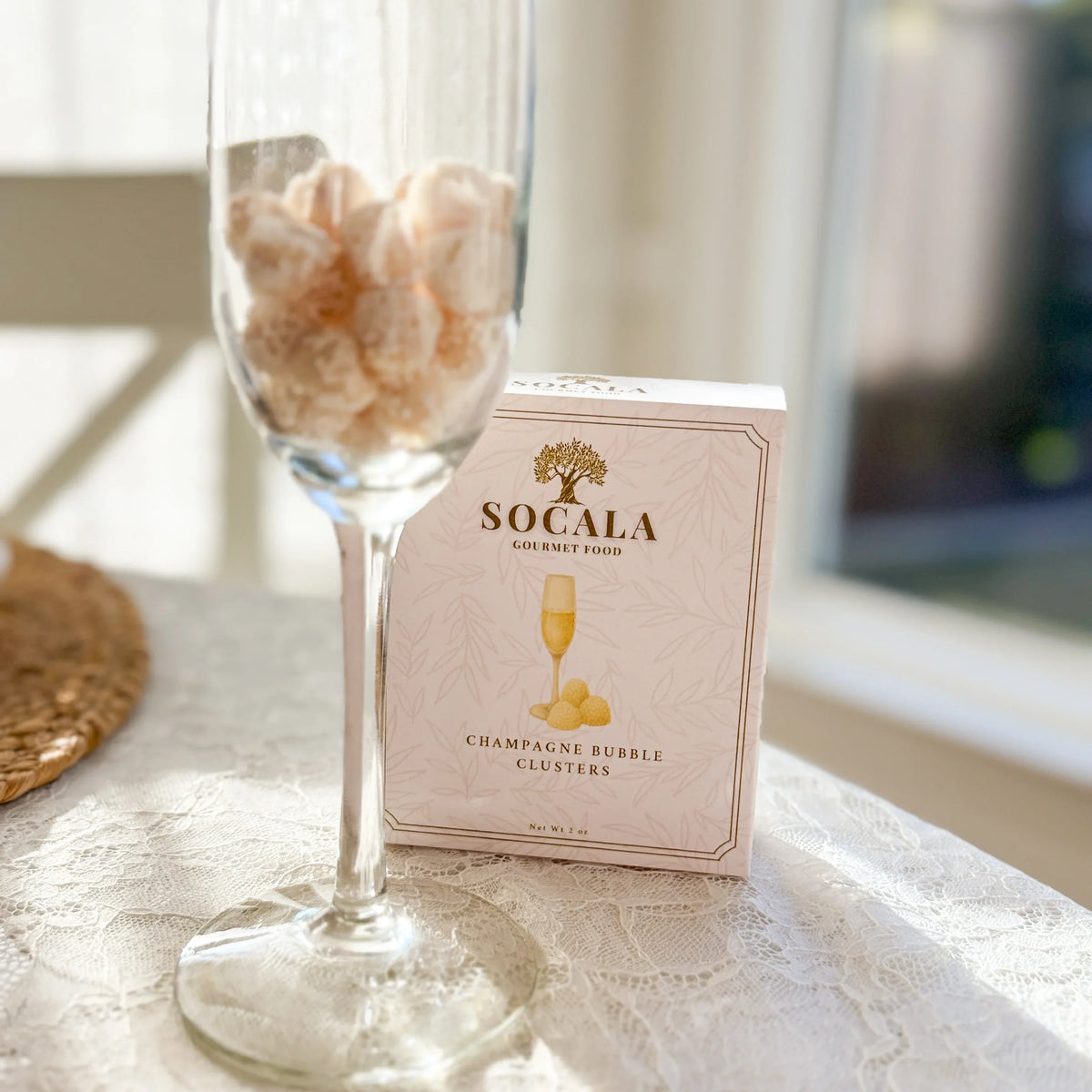 SOCALA Champagne Bubble Clusters box and confections presented in a glass.