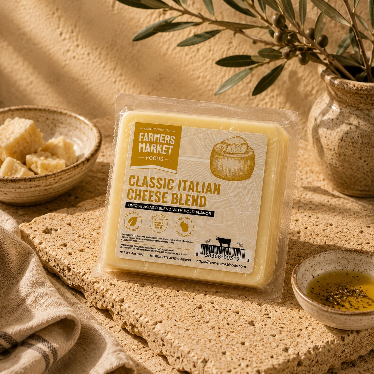 A packaged block of Farmers Market Foods Classic Italian Cheese Blend cheese sits on a textured stone surface with olive branches, a small bowl of cheese, and a dish of oil around it.