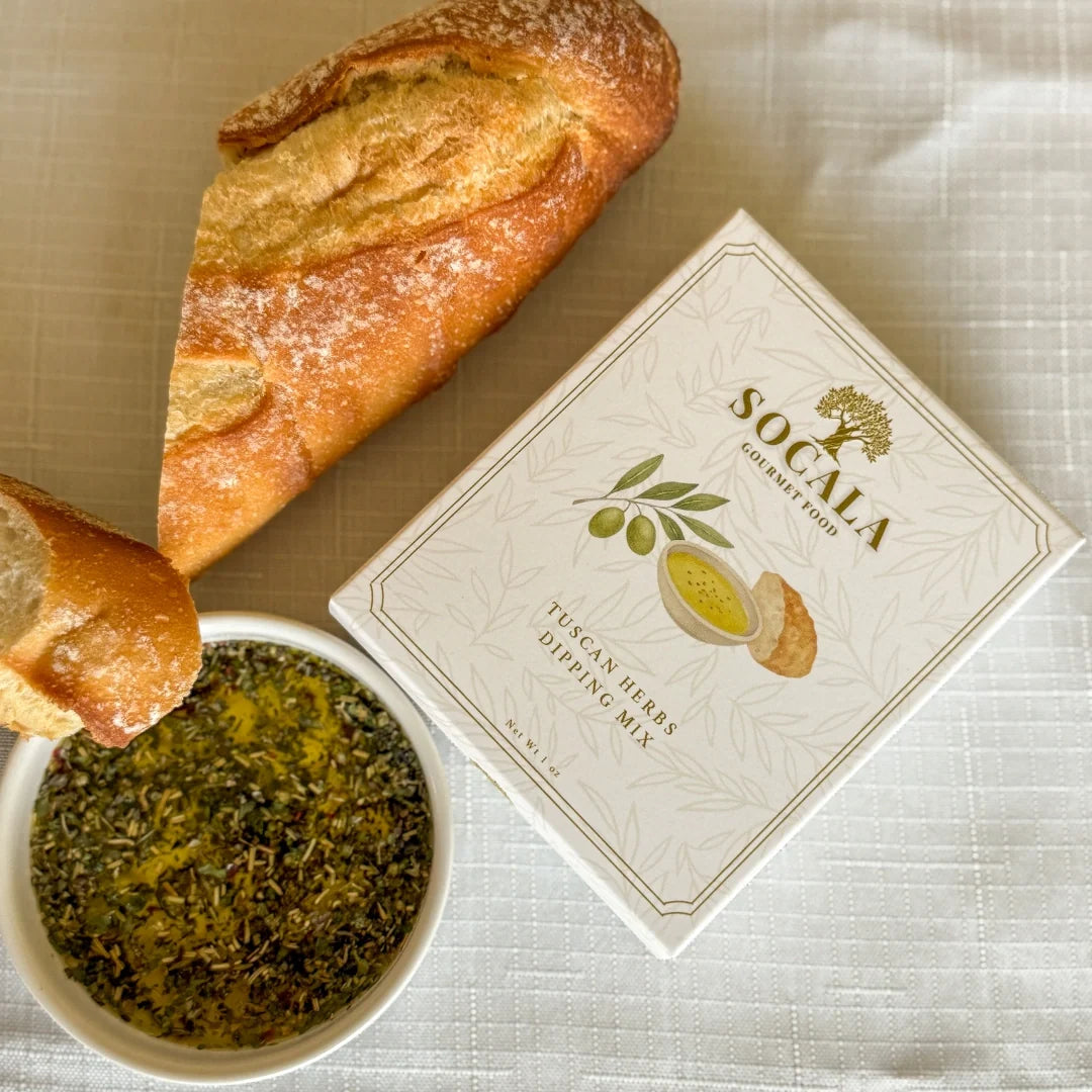 Box of Socala Tuscan Herb Dipping Mix with bread and herbs on a textured surface